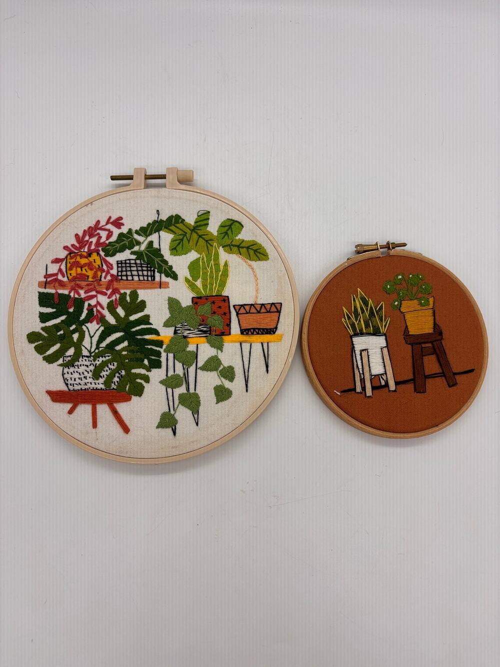 Two hand embroidered crewel plant scene pictures in hoops